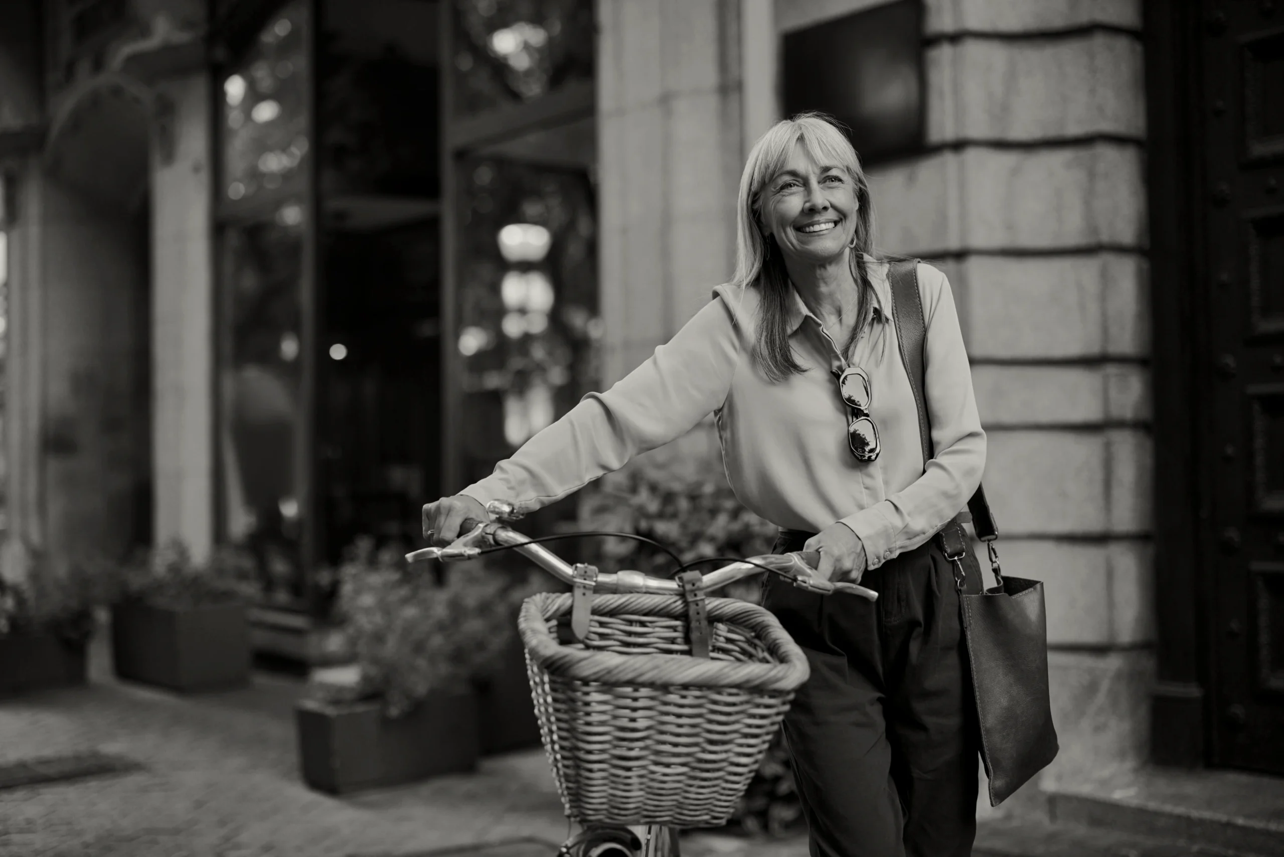 Older woman holding a basket of fresh produce outdoors.