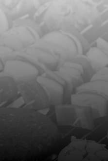 Black and white image of meat and vegetables on skewers on the grill